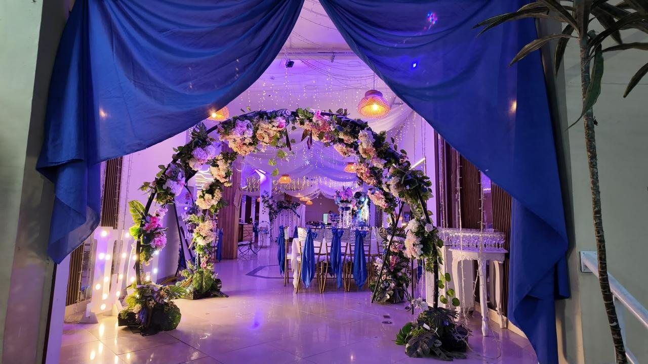 Arco floral y cortinas azules a la entrada de un salón de bodas